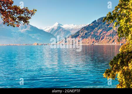 Farbenfrohe Herbstansicht des Zeller Sees im Morgennebel mit Großglockner-Gipfel im Hintergrund. Sonnenszene am Morgen von Österreich, Europa, Zell am See Stadt. Stockfoto