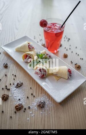 Pfannkuchenbrötchen mit Quark und Erdbeere und roter Limonade trinken Sie im Glas Stockfoto