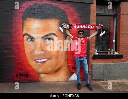 Ein Manchester United-Fan posiert vor einem Wandbild von Cristiano Ronaldo vor dem Premier League-Spiel in Old Trafford, Manchester. Bilddatum: Samstag, 25. September 2021. Stockfoto