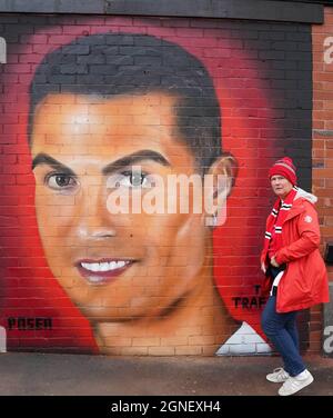 Ein Manchester United-Fan posiert vor einem Wandbild von Cristiano Ronaldo vor dem Premier League-Spiel in Old Trafford, Manchester. Bilddatum: Samstag, 25. September 2021. Stockfoto