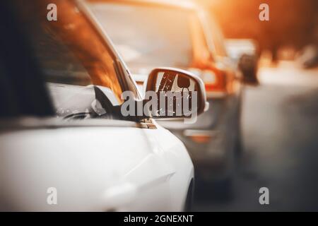 Rückansicht eines weißen Neuwagens mit reflektierenden Seitenscheiben und einem Rückspiegel an einem sonnigen Herbsttag. Verkehr. Stockfoto