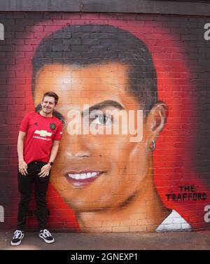 Ein Manchester United-Fan posiert vor einem Wandbild von Cristiano Ronaldo vor dem Premier League-Spiel in Old Trafford, Manchester. Bilddatum: Samstag, 25. September 2021. Stockfoto