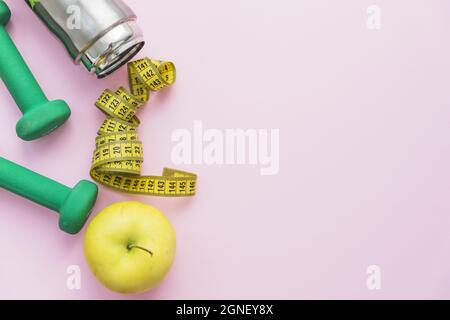 Kurzhanteln Wasserflasche Messband Apfel rosa Hintergrund. Hohe Qualität und Auflösung schönes Fotokonzept Stockfoto