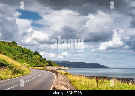 Kurvenreiche Straße, die durch die Küste zu den Bergen in weiter Ferne führt, Wild Atlantic Way, Nordirland Stockfoto