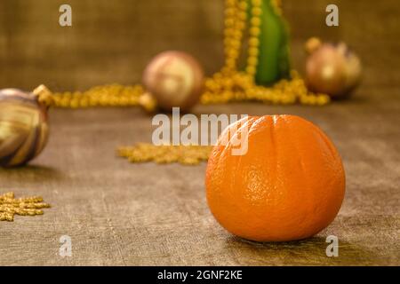 Komposition zum neuen Jahr. Auf dem Tisch stehen eine orange und weihnachtliche Dekoration: goldene Kugeln, Schneeflocken und Perlen. Nahaufnahme. Selektiver Fokus. Speicherplatz kopieren Stockfoto