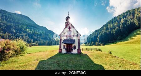 Panoramablick auf die Kirche San Giovanni im Dorf St. Magdalena. Sonnige Sommerszene im Villnob-Tal mit den Bergen der Geisler Gruppe auf dem Rücken Stockfoto