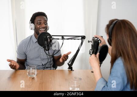 Menschen mit mehreren Rassen, die einen Podcast mit Mikrofon und Kopfhörern aus dem Heimstudio aufnehmen Stockfoto