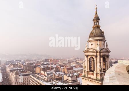 Blick auf Budapest von der St. Stephens Basilika, Budapest, Ungarn an einem verschneiten nebligen Tag. Schnee liegt auf den Dächern von Häusern Stockfoto