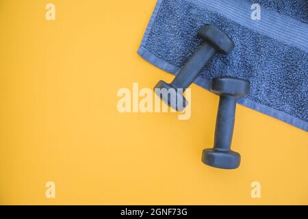 Kurzhanteln Handtuch gelben Hintergrund. Hohe Qualität und Auflösung schönes Fotokonzept Stockfoto
