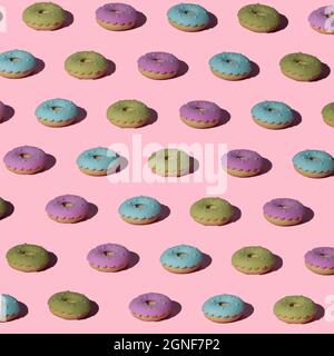 Grünes, blaues und pinkfarbenes Donuts-Layout auf trendigem pastellrosa Hintergrund. Nahtloses Muster. Draufsicht. Minimales Essen und Sommerkonzept. Stockfoto