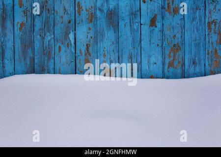 Blauer Holzstruktur Hintergrund mit unberührtem Schnee, abblätternde Farbe auf Holz im Winter Stockfoto