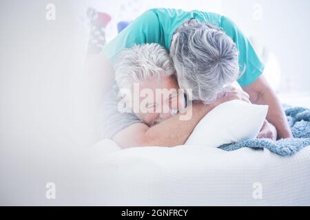 Ältere Paare spielen und haben Spaß auf dem Bett. Ältere Paare genießen miteinander. Sorglos altes Paar mit grauen Haaren Spaß verbringen Freizeit t Stockfoto