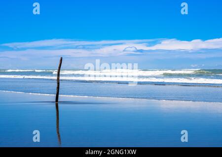 Raue Wellen auf dem Meer aus der Nähe vom Strand unter dem blauen Himmel Stockfoto