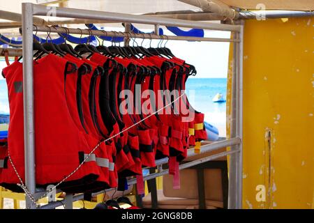 Schwimmwesten, die an einem Gestell hängen. Rote Schwimmwesten für Wassersport. Stockfoto