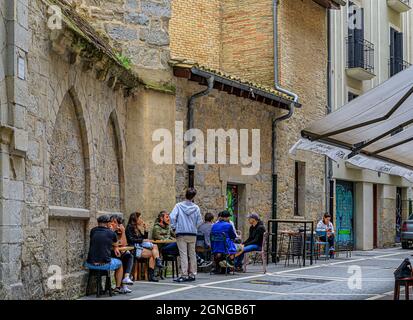 Pamplona, Spanien - 20. Juni 2021: Menschen in einem Straßencafé an der Steinfassade der Kirche Iglesia de San Saturnino, bekannt als San Cernin in der Altstadt Stockfoto