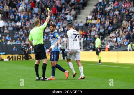 MILTON KEYNES, Großbritannien, 25. SEPTEMBER Schiedsrichter Scott Oldham zeigt Milton Keynes Dons Daniel Harvie in der zweiten Hälfte des Sky Bet League One-Spiels zwischen MK Dons und Wycombe Wanderers am Samstag, 25. September 2021, im Stadium MK, Milton Keynes eine gelbe Karte. (Kredit: John Cripps | MI Nachrichten) Kredit: MI Nachrichten & Sport /Alamy Live Nachrichten Stockfoto