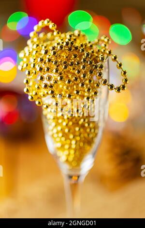 Zwei Sektgläser mit Weihnachtsperlen. Weihnachtsdekorationen im rustikalen Stil auf hellem Hintergrund mit Lichtern. Kiefernzapfen und brennende Kerzen an Stockfoto