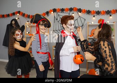 Gesichtsfarbe Künstler Anwendung gruselig Make-up auf Gruppe von Kindern auf Spaß Halloween-Party zu Hause Stockfoto