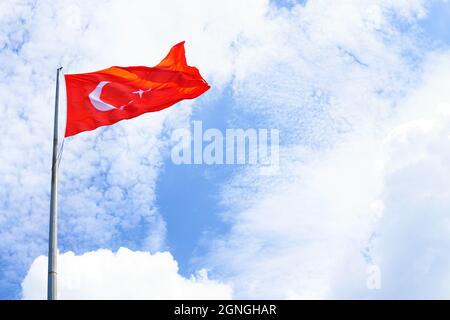 Blick auf die Flagge der Türkei, die an einem sonnigen Tag gegen den blauen Himmel schwenkt Stockfoto