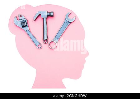 Cut-out Frau Kopf Profil Silhouette mit einem Kit von kleinen Handwerkzeugen aus Stahl isoliert auf weiß. Frauen in Technik und Technik. Stockfoto