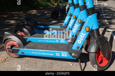 E-freundliche Dott Electric Scooter, die vor einer S-Bahnstation im Südwesten Londons, England, Großbritannien, geparkt sind Stockfoto