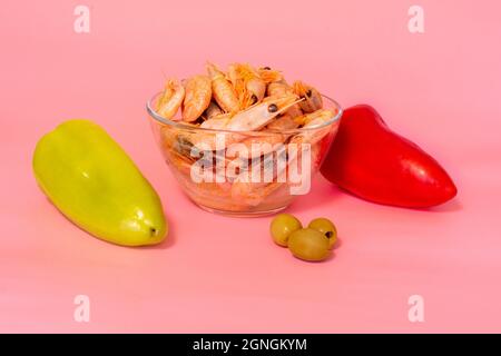 Frisch gefärbte Paprika und gekochte Garnelen auf rosa Hintergrund, gesundes Lebensmittelkonzept Stockfoto