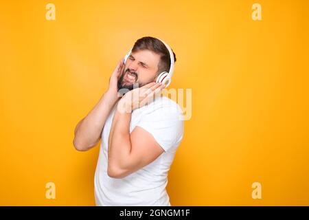 Der Mann verengte seine Augen, drückte seine Hände auf die Kopfhörer und hörte fleißig Musik. Stockfoto