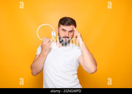Bärtiger Mann, Musikliebhaber hält weiße Kopfhörer vor sich. Stockfoto