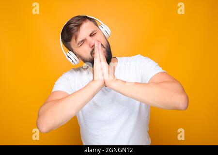 Bärtiger Mann faltete seine Handflächen vor seinem Gesicht und lauscht emotionaler Musik. Stockfoto