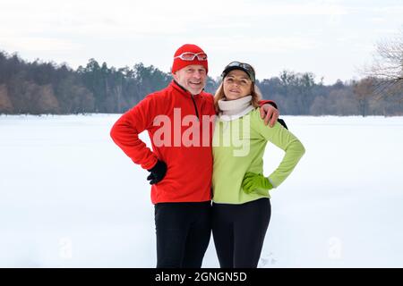 Lächelndes reifes Paar, das im Winter im Park umarmt Stockfoto