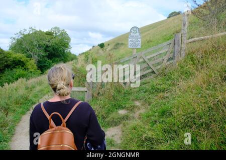 Kaukasische Frau vor einem Schild des National Trust für Cerne Abbas Chalk Giant Figur in Dorset Stockfoto