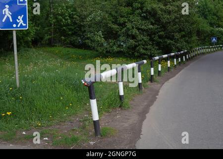 Weißer schwarzer Zaun entlang der Straße. Ein Zaun vom illegalen Parken. Straßenschutz. Stockfoto