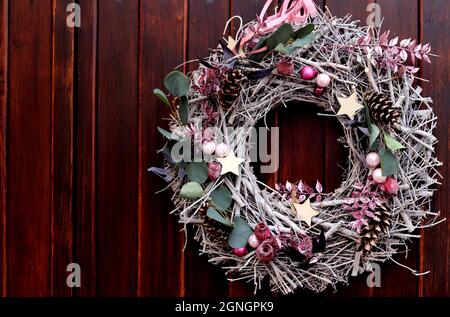 Pinkfarbener Weihnachtskranz auf dunklem Holzhintergrund Stockfoto