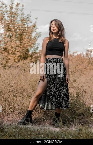 Ein junges Mädchen mit dunklen Haaren steht auf einem herbstlichen Hintergrund. Stockfoto