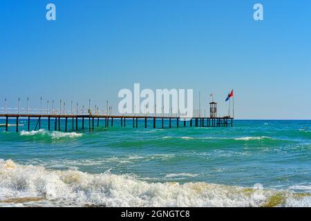 Wellen an der Türkisenküste von Manavgat Antalya und Pier mit türkischer Flagge Stockfoto