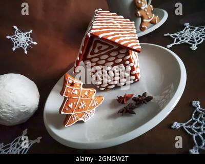 Lebkuchenhaus und weihnachtsbaum mit weißer Glasur in Neujahrsmustern mit drei Anissternen serviert dekoriert Stockfoto