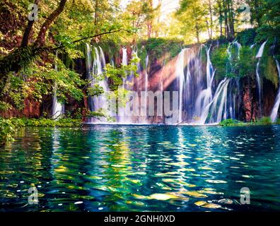 Letztes Sonnenlicht erhellt den reinen Wasserfall im Plitvice National Park. Bunte Frühlingsszene von grünem Wald mit blauem See. Tolle Landschaft vi Stockfoto