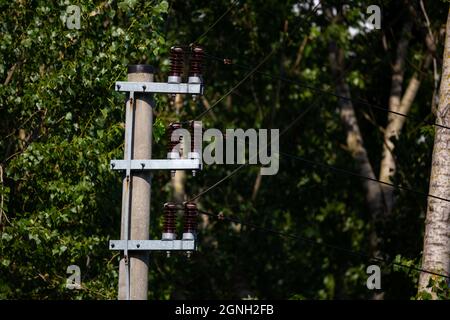 Keramikisolatoren an Niederspannungspylonen. Foto aufgenommen bei guten Lichtverhältnissen an einem sonnigen Tag. Stockfoto