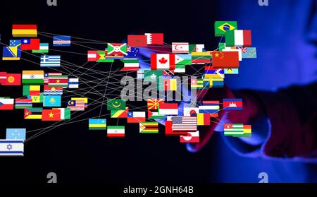3D-Rendering von internationalen Flaggen globaler Partner mit verschwommener dunkler männlicher Hand im Hintergrund Stockfoto