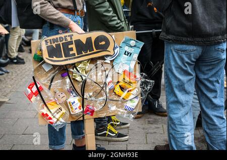 Lübeck, 24. September 2021: Junge Studentin hält ein kreatives Protestschild aus Pappe, das mit viel Plastikmüll und Texterfassung verklebt ist Stockfoto