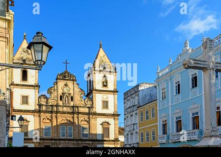 Fassade einer alten historischen Kirche und farbenfrohe Häuser im Kolonialstil am zentralen Platz des Pelourinhoviertels in Salvador, Bahia Stockfoto