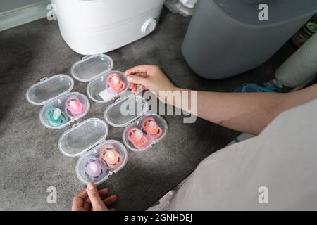 Nahaufnahme einer unbekannten Frau, die die Hand voll Schnuller in einem Plastikbehälter auf dem Küchentischtisch hält Stockfoto