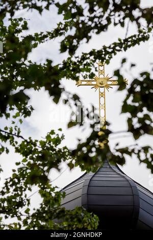 Christliches Kreuz auf der Zwiebelkuppel der Kirche. Vergoldetes Kirchenkreuz. Stockfoto