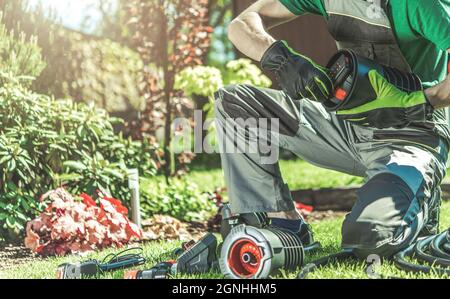 Automatische Backyard Garten Bewässerung System Installation durchgeführt von professionellen kaukasischen Garten Techniker. Automatische Rasensprinkler Stockfoto