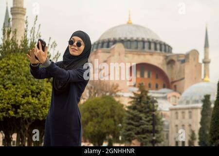 Ein junges lächelndes muslimisches Mädchen in einem Hijab und einer stilvollen schwarzen Brille macht. Stockfoto