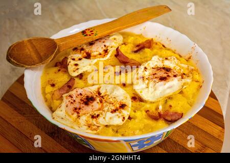 Rumänisches traditionelles Gericht mit Polenta, Speck, Käse und gebratenem Ei namens „Bulz“. Stockfoto