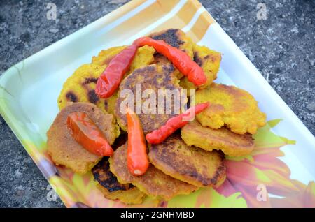 Nahaufnahme der Bund gelb braun bengalen Gramm gebratenes Essen mit rot kühl in der Platte über unscharf grau braunen Hintergrund. Stockfoto