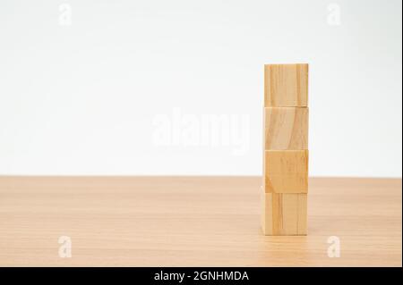 Holzwürfel auf einem Holztisch mit weißem Hintergrund gestapelt Stockfoto