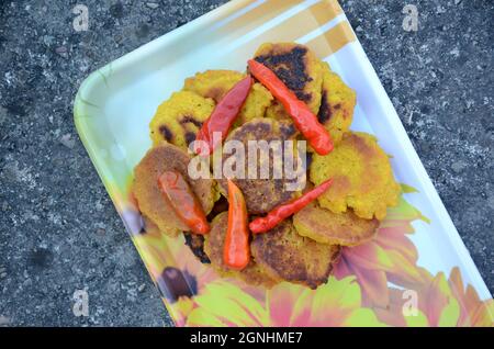 Nahaufnahme der Bund gelb braun bengalen Gramm gebratenes Essen mit rot kühl in der Platte über unscharf grau braunen Hintergrund. Stockfoto