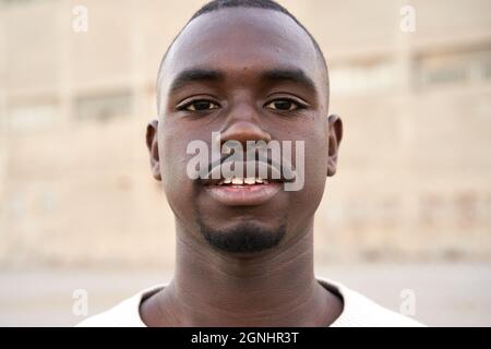 Junger afrikanischer Mann, der die Kamera im Freien betrachtet. Stockfoto